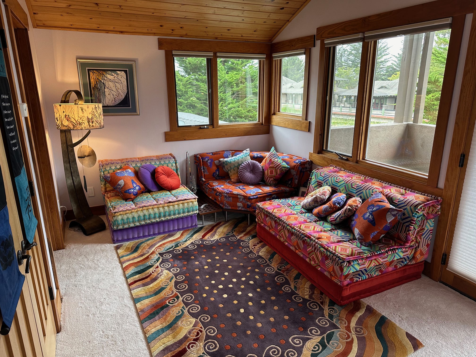 Modular Mah Jong sofas in mixed patterned fabrics with teak gap tables and a sofa base arranged in a sunlit corner with a striped area rug