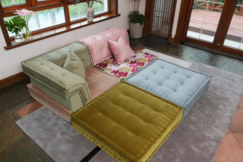 Corner piece of a colorful modular sofa with mixed corduroy and floral cushions