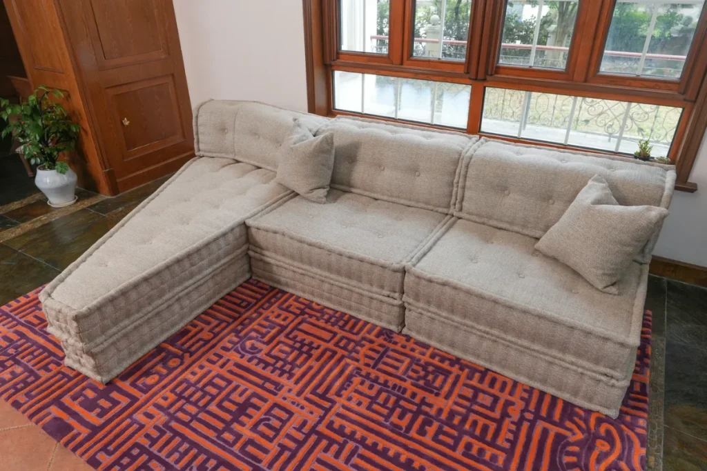 Fully custom beige modular sofa with an extended chaise lounge in the shape of a pizza and matching cushions
